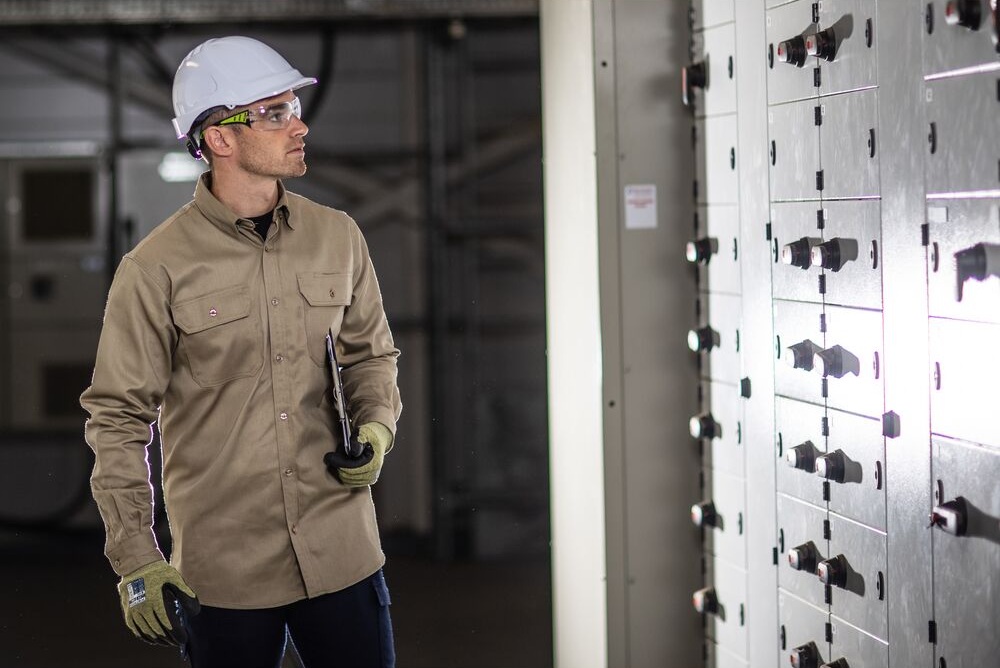 Profissional com capacete e óculos a inspecionar painel técnico